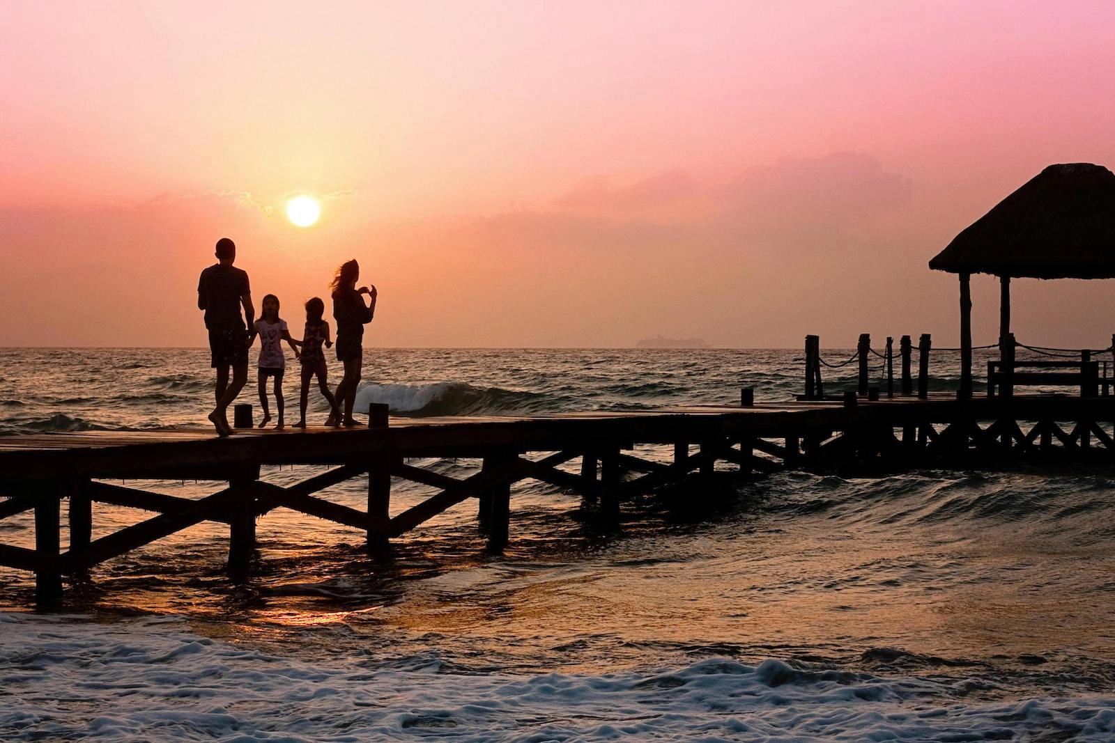 A family walking hand in hand on a pier at sunset